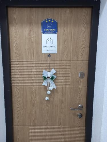 a wooden door with a sign and a bow on it at Apartmani Martenovic 1 in Vrnjačka Banja