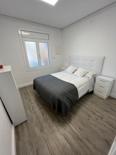 a white bedroom with a bed and a window at Apartamento en la playa. Free Parking. Free WiFi in L'Escala