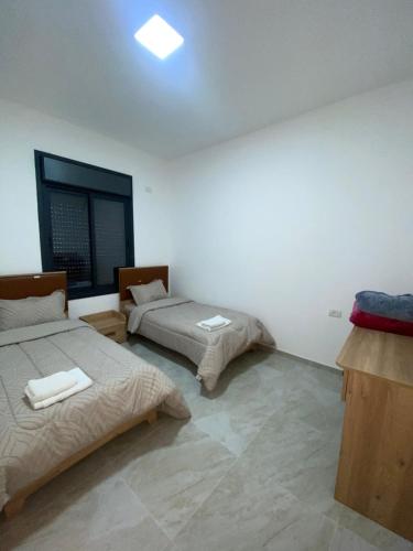 a bedroom with two beds and a window at Alfred Apartments in Ramallah