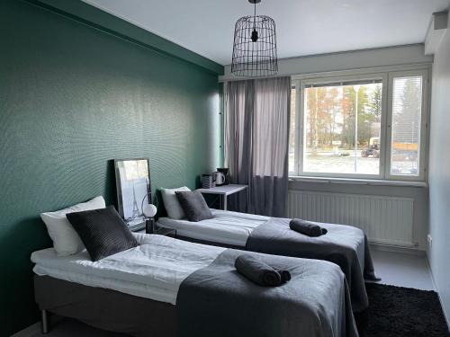 two beds in a room with green walls at Iso huoneisto 4 in Ylivieska