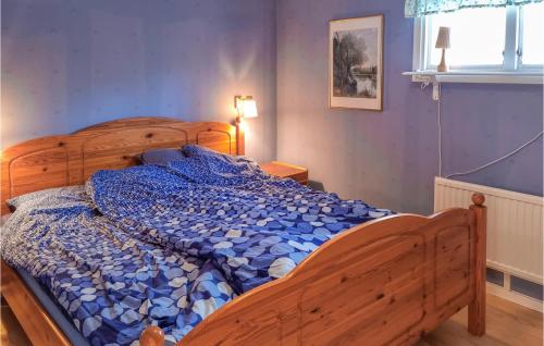 FjälkingeにあるAwesome Home In Fjlkinge With Kitchenのベッドルーム1室(木製ベッド1台、青い掛け布団付)