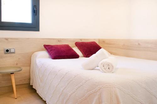 a bed with red and white pillows on it at Moderno y confortable apartamento Port Trebol in Roses