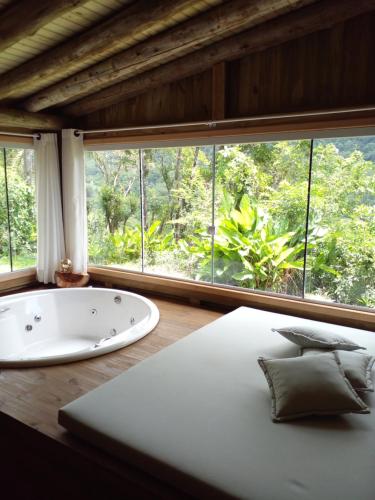 a bathroom with a tub and a large window at Pousada Flor de Lótus dos Canyons in Praia Grande
