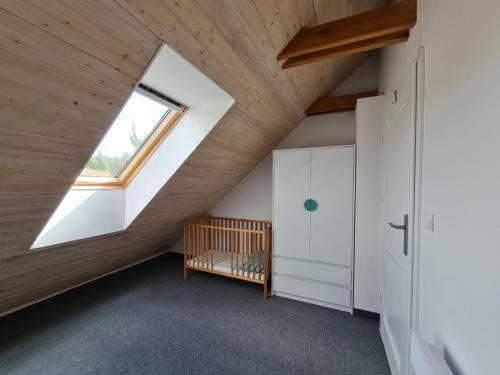 an attic bedroom with a skylight and a crib at Mak i Rumianek in Parzeńsko