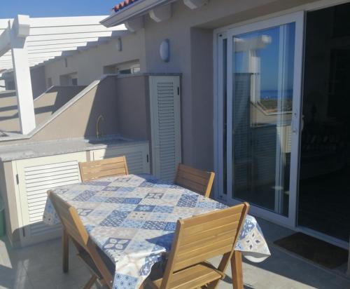 een balkon met een tafel en stoelen op een patio bij Attico IL SOLE in Castelsardo