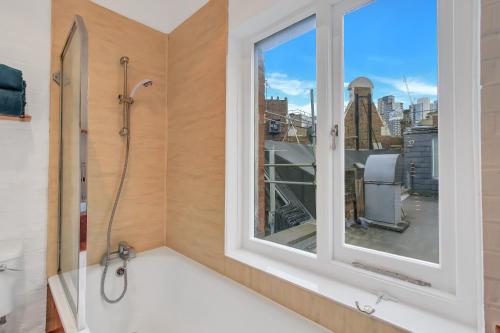 a bathroom with a bath tub and a window at Stunning Shoreditch Loft Warehouse Style Apartment in London