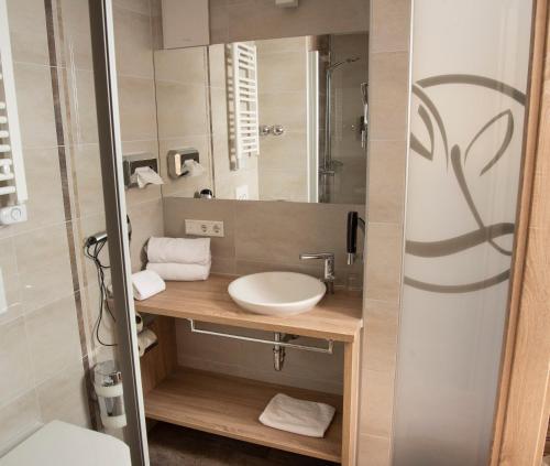 ein Bad mit einem Waschbecken und einem Spiegel in der Unterkunft Gasthof zum Goldenen Lamm in Wettelsheim
