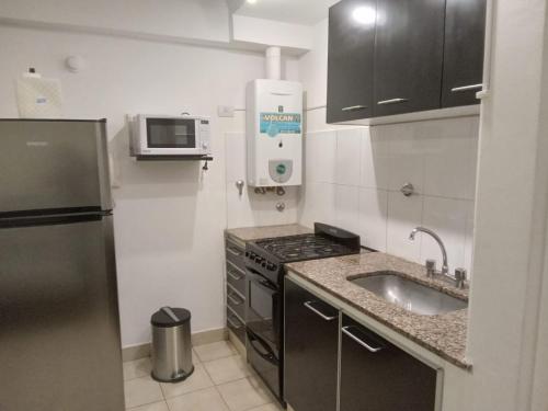 a small kitchen with a sink and a microwave at Monteagudo 847 in San Miguel de Tucumán