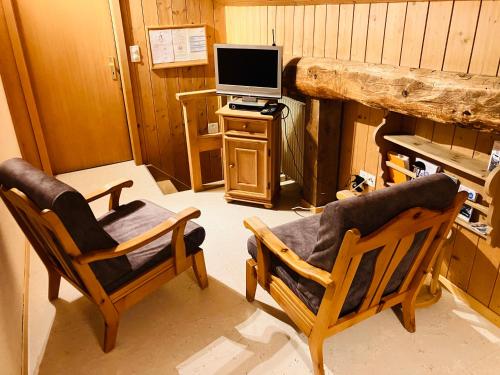een woonkamer met 2 stoelen en een televisie bij Chesa Margadant in Zuoz
