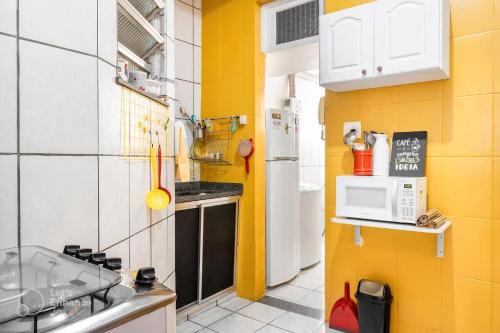 a small kitchen with yellow walls and a white refrigerator at Hotel Mama! Copacabana (Posto1 -Leme) in Rio de Janeiro