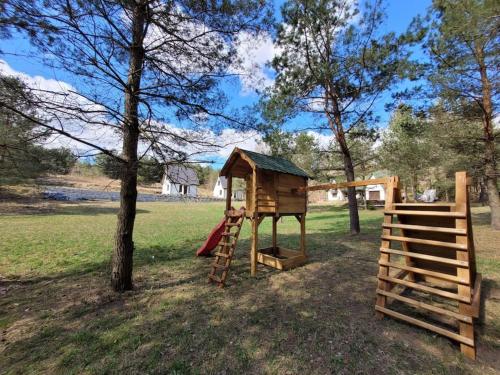 un parco giochi con una casa sull'albero e uno scivolo di Uroczy domek na Mazurach, Pilec 59 a Pilec