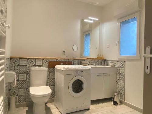 uma casa de banho com uma máquina de lavar roupa e um WC em Le defi em Fouras
