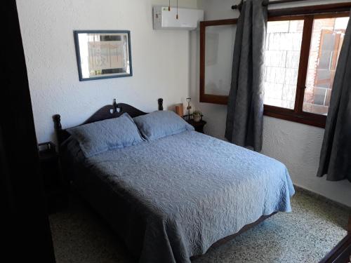 a bedroom with a bed with a blue comforter and a window at En Suíte - Habitación con baño privado - Entrada independiente in Punta del Este