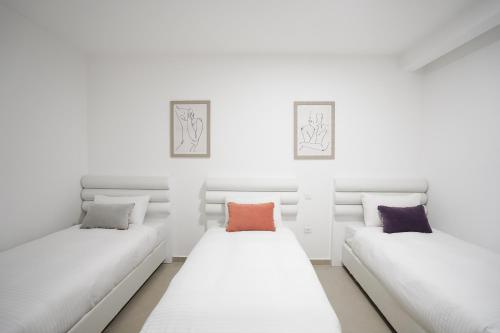 two beds in a room with white walls at Golf Residence By Sun and View in Eilat