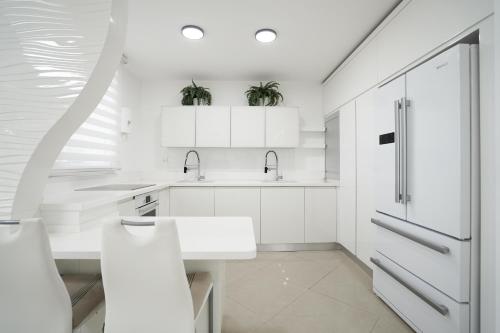 una cocina blanca con armarios blancos y fregadero en Golf Residence By Sun and View en Eilat