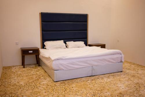 a bedroom with a bed with a blue headboard and two tables at منتجع وإسطبل الهدوء in Riyadh