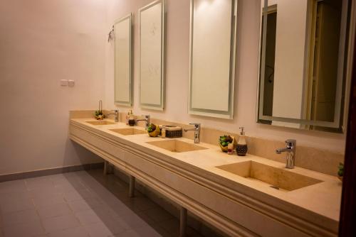 a bathroom with three sinks and two mirrors at منتجع وإسطبل الهدوء in Riyadh