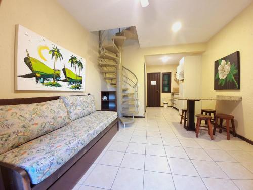 a living room with a couch and a staircase at Villa Garoupeta - Apartamentos in Bombinhas