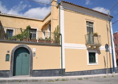 a yellow building with a blue door and a balcony at B&B VELARDI in Viagrande