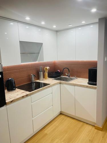 a kitchen with white cabinets and a sink at TALIA Apartament Tatarska 4 in Przemyśl