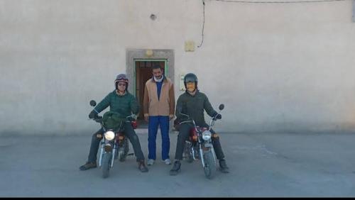 un grupo de tres hombres parados junto a sus motocicletas en Chez L'habitant Brahim kanih 