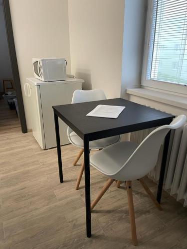 a black table with two white chairs and a microwave at Apartment Patera 2 in Meziboři