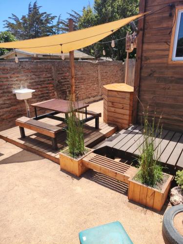 a patio with a picnic table and a yellow umbrella at RdA Cabaña in Pichilemu