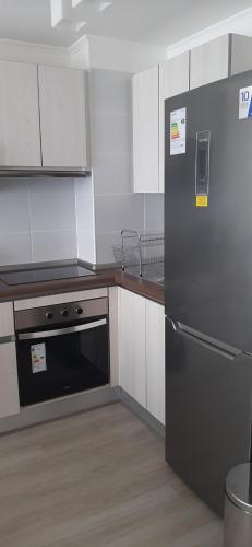 a kitchen with a stainless steel refrigerator and white cabinets at Bonito y Acogedor Dpto Av Pacífico 3100, La Serena in La Serena