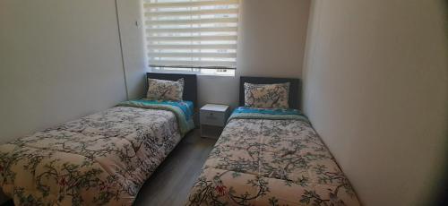 2 camas en una habitación pequeña con ventana en Bonito y Acogedor Dpto Av Pacífico 3100, La Serena en La Serena