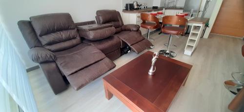 a living room with a brown couch and a table at Bonito y Acogedor Dpto Av Pacífico 3100, La Serena in La Serena