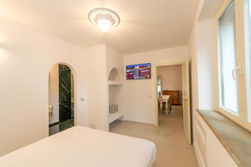 a white bedroom with a bed and a window at Garden Relais Le Fontanelle in Montescudaio