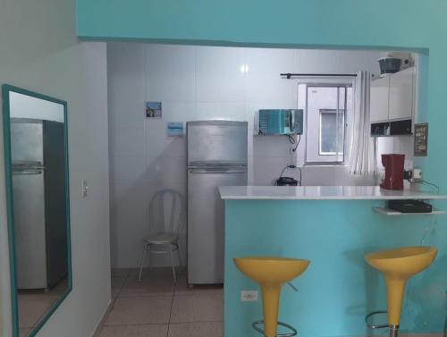 a kitchen with two yellow bar stools in it at Kit Relu in Praia Grande