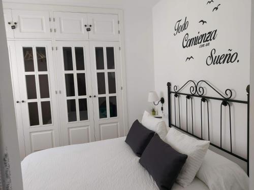 a bedroom with a black and white bed and white walls at ÁTICO VICTORIA BEACH in Cádiz
