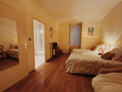 a bedroom with two beds and a door to a balcony at Gîte Les Roches : maison de caractère pour 15 personnes in Saint-Romain