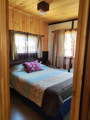 Dormitorio con cama con almohada morada en RdA Cabaña en Pichilemu