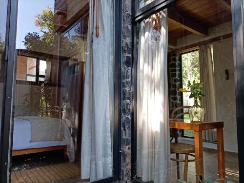 a room with a glass door with a table and a window at Canto de Aves in Malinalco