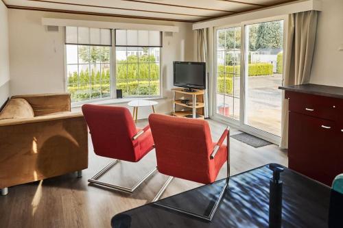 - un salon avec deux chaises rouges et une télévision dans l'établissement 4 persons chalet Valkenbosch situated in the forested area, à Oisterwijk