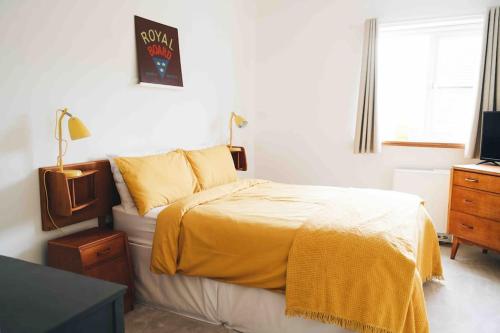 a bedroom with a bed with a yellow blanket at Clee Ness - 1 bed maisonette, on the seafront in Cleethorpes