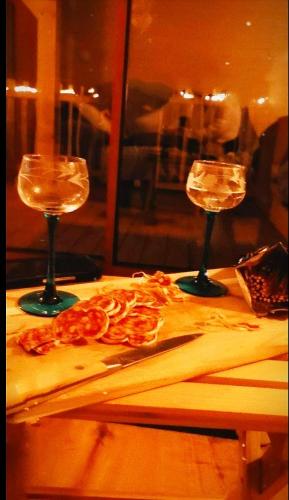 two wine glasses sitting on a table with a cutting board at La cabane au bain perché in Aspach