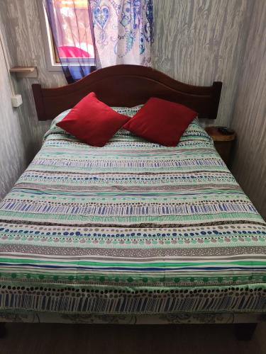a bed with two red pillows on top of it at RdA Habitación para dos in Pichilemu