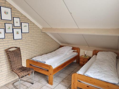 two beds and a chair in a attic room at Vakantiehuis Ome Wim op 't Hoogelandt in De Koog