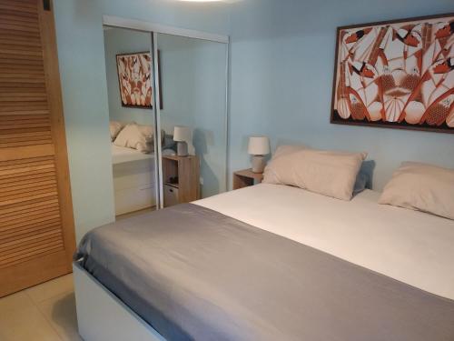 een slaapkamer met een wit bed en een spiegel bij Kas di BaMi A-186 op Seru Coral Resort - Ruim appartement met groot zwembad en tropische tuin in Willemstad