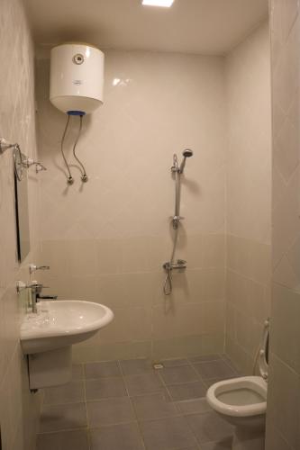 a white bathroom with a toilet and a sink at Al-Mwadda Hotel in Seeb