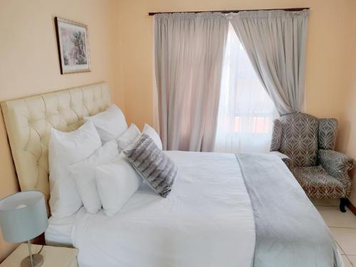 1 dormitorio con 1 cama blanca con silla y ventana en Sunrise Guesthouse en Pretoria