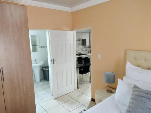 1 dormitorio con 1 cama y baño con lavamanos en Sunrise Guesthouse, en Pretoria