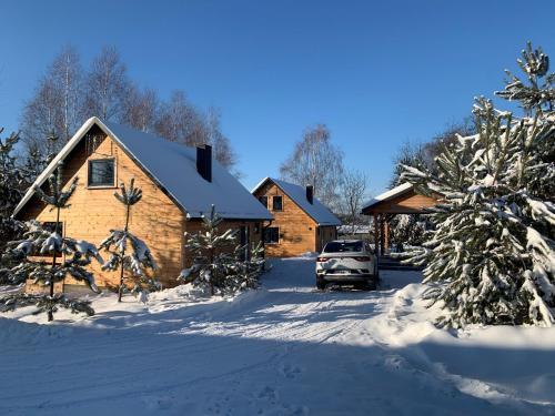 a log cabin in the snow with a truck parked in the driveway at Roztocze- Domki w Zagajniku in Blizów
