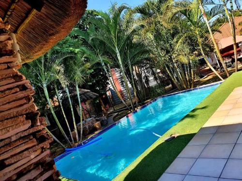 een zwembad in een resort met palmbomen bij MAKWATAMBANI GUEST MANOR in Thohoyandou