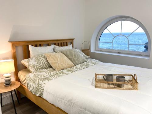 a bed with a basket on it with a window at Unique Waterfront Duplex on the Mediterranean - Caleta, Catalan Bay in Gibraltar