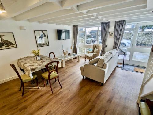 een woonkamer met een tafel en stoelen en een bank bij 2 Stable Cottage, Llanbethery in Llancarvan