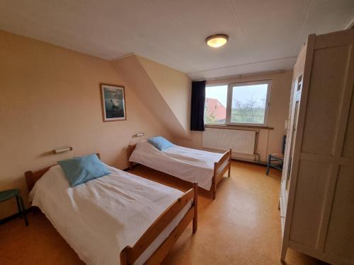 a room with two beds and a window at Westzicht in Den Burg